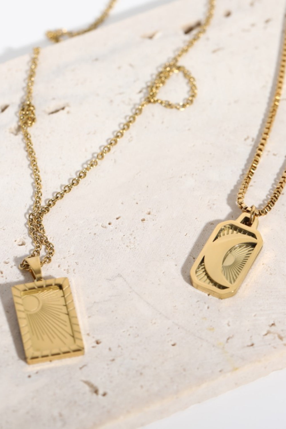 18K gold-plated celestial pendant necklaces, one with a sun, one with a moon, on delicate chains.