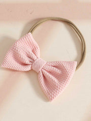 Pink textured bow headband with a tan elastic band.