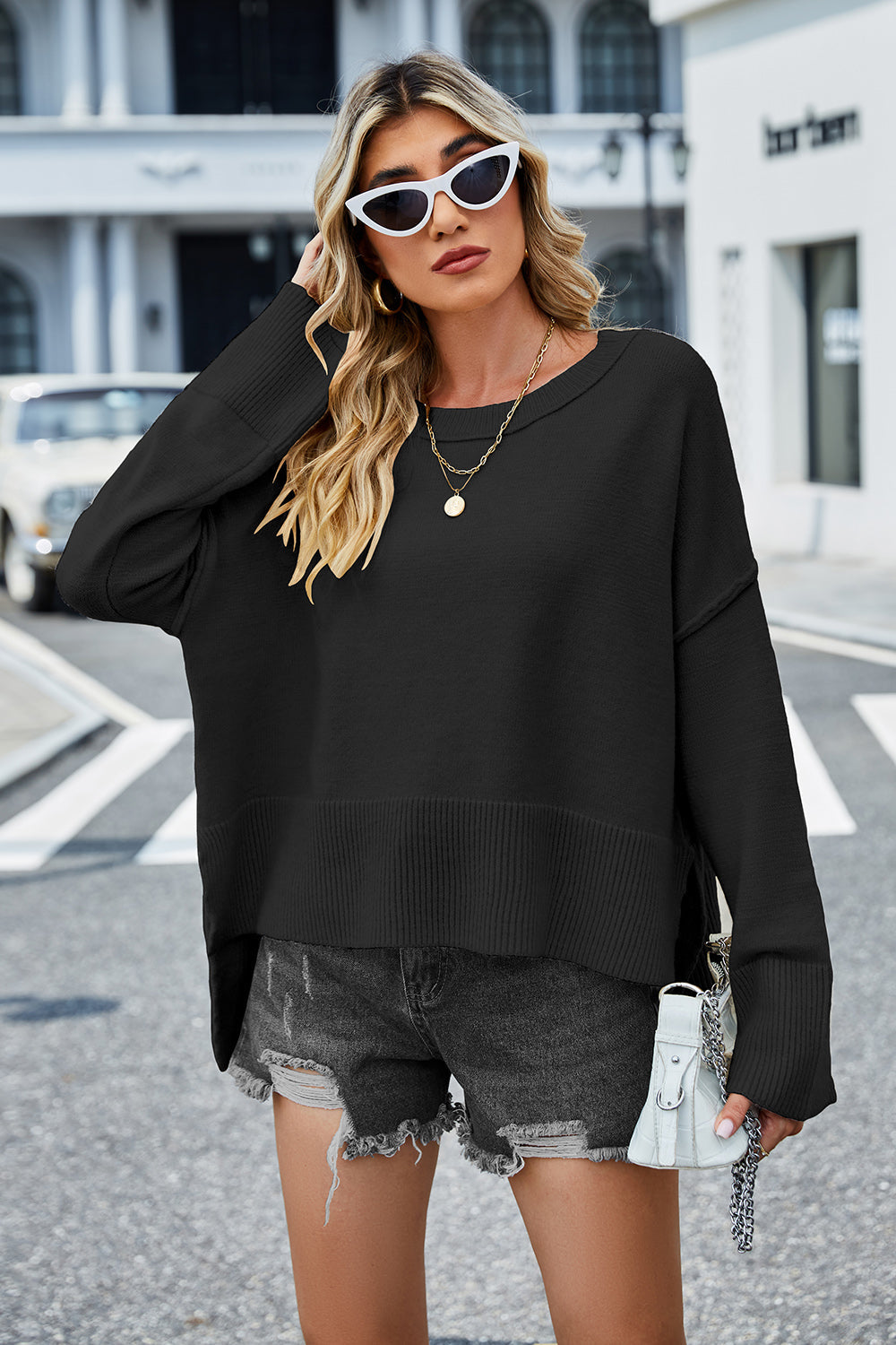 Black acrylic knit sweater with flared sleeves and slit hem detail.