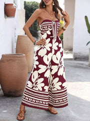 Burgundy floral tie-front strapless wide-leg romper with white print and border detail.