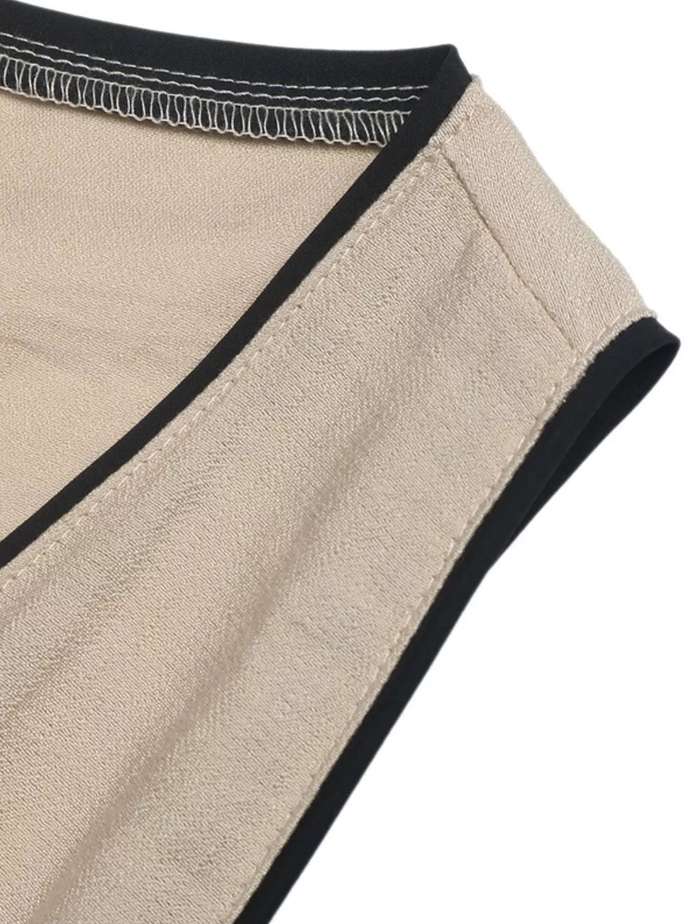 Elegant beige maxi dress detail with black piping and contrast stitching.