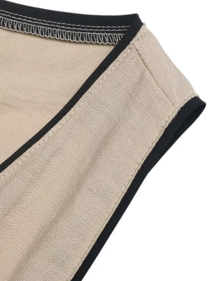Elegant beige maxi dress detail with black piping and contrast stitching.