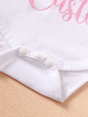 White cotton baby bodysuit with pink embroidery and snap closure detail.
