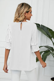 White blouse with pleated sleeves and smocked cuffs.