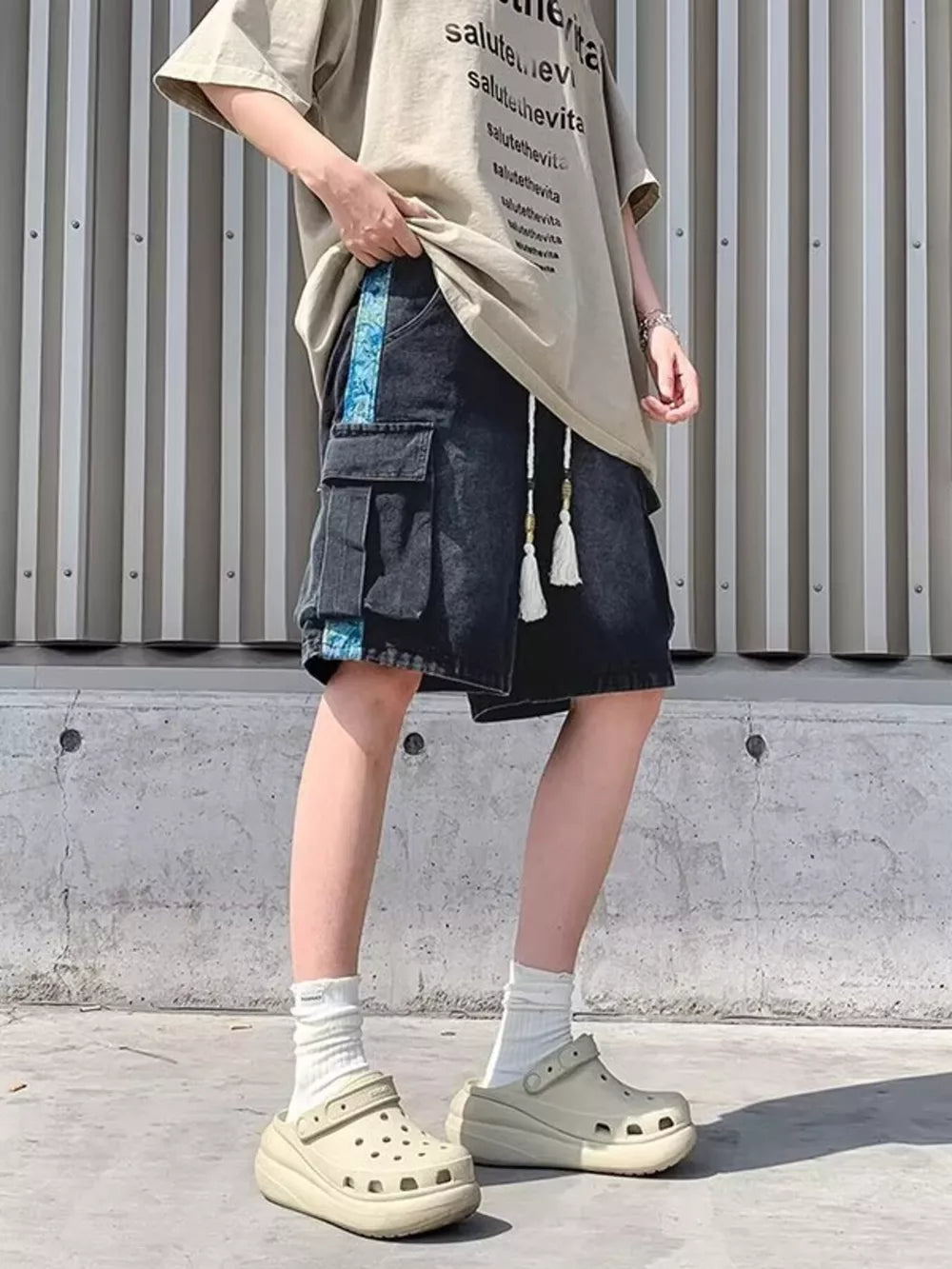 Black denim cargo shorts with braided drawstring and blue side stripe detail.