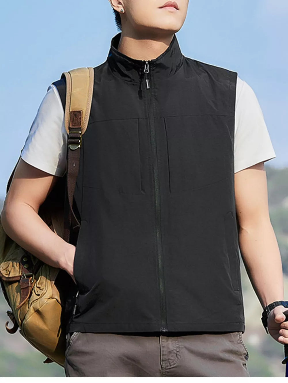 Black zip up vest with stand collar and chest pockets, worn over white t-shirt.