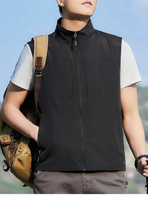 Black zip up vest with stand collar and chest pockets, worn over white t-shirt.