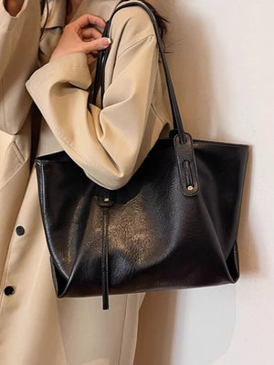 Elegant large black pu leather shoulder bag with a slouchy design and tassel detail.
