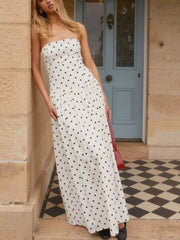 White polka dot strapless maxi dress with tiered skirt and ruffled hem.