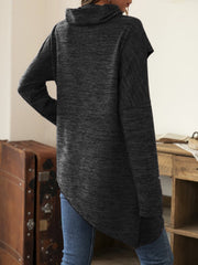 Gray knit asymmetric sweater with cowl neck and long sleeves, styled with jeans.