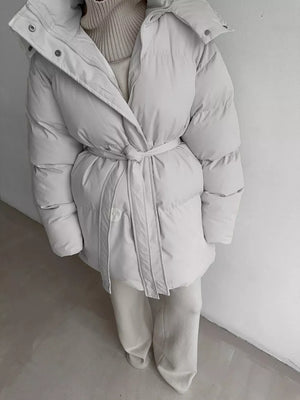 Ivory white belted puffer trench coat with hood and buttoned closure.