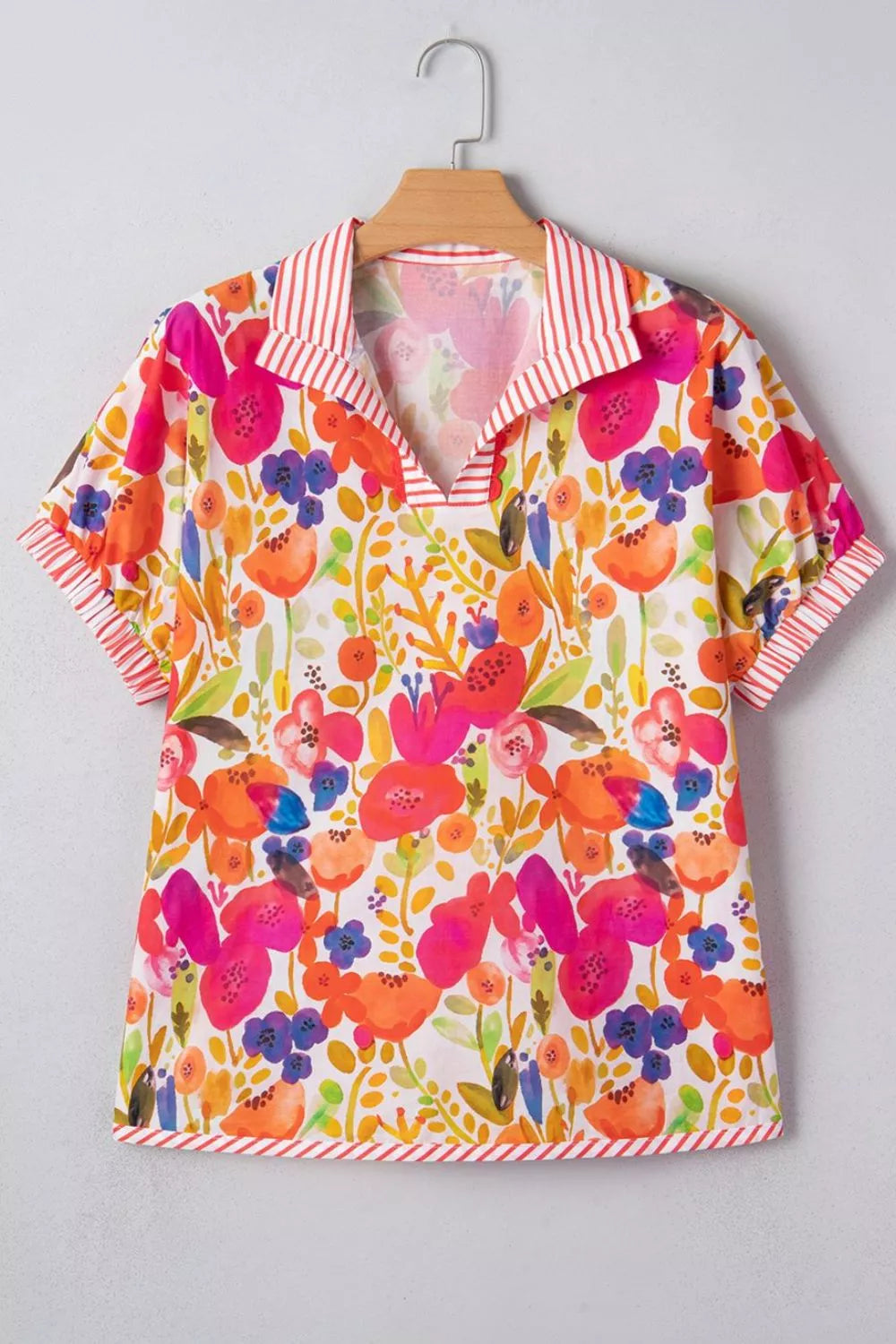 Floral print collared cotton blouse with striped trim and short sleeves.