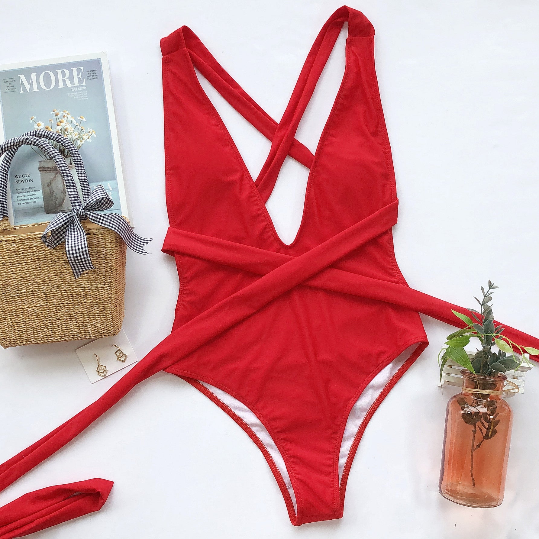 Red wrap-around halterneck plunge swimsuit with crisscross straps and a tie waist.