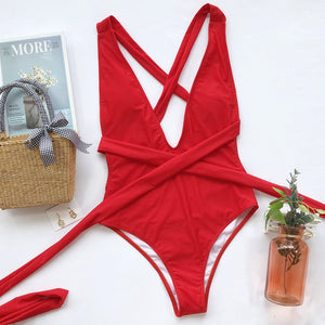 Red wrap-around halterneck plunge swimsuit with crisscross straps and a tie waist.