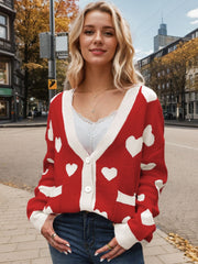 Red acrylic cardigan with white heart intarsia, button front, and contrast trim.
