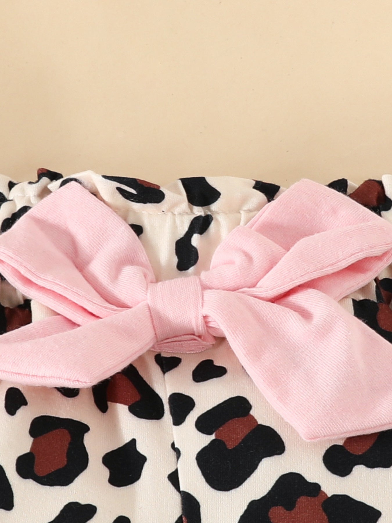 Baby bodysuit with pink bow detail and leopard print.