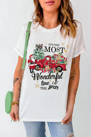 White graphic tee with Santa, Christmas tree, and red truck loaded with gifts.