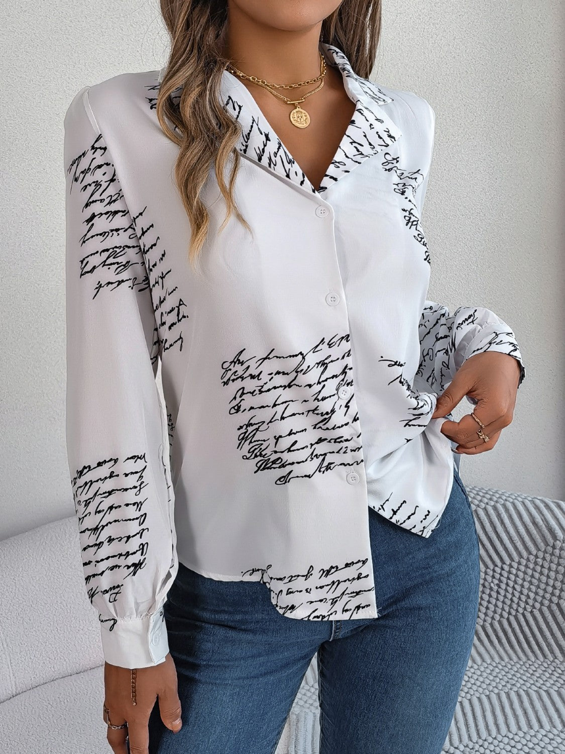 White collared blouse with black script print, button front, and long sleeves.
