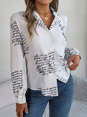 White collared blouse with black script print, button front, and long sleeves.
