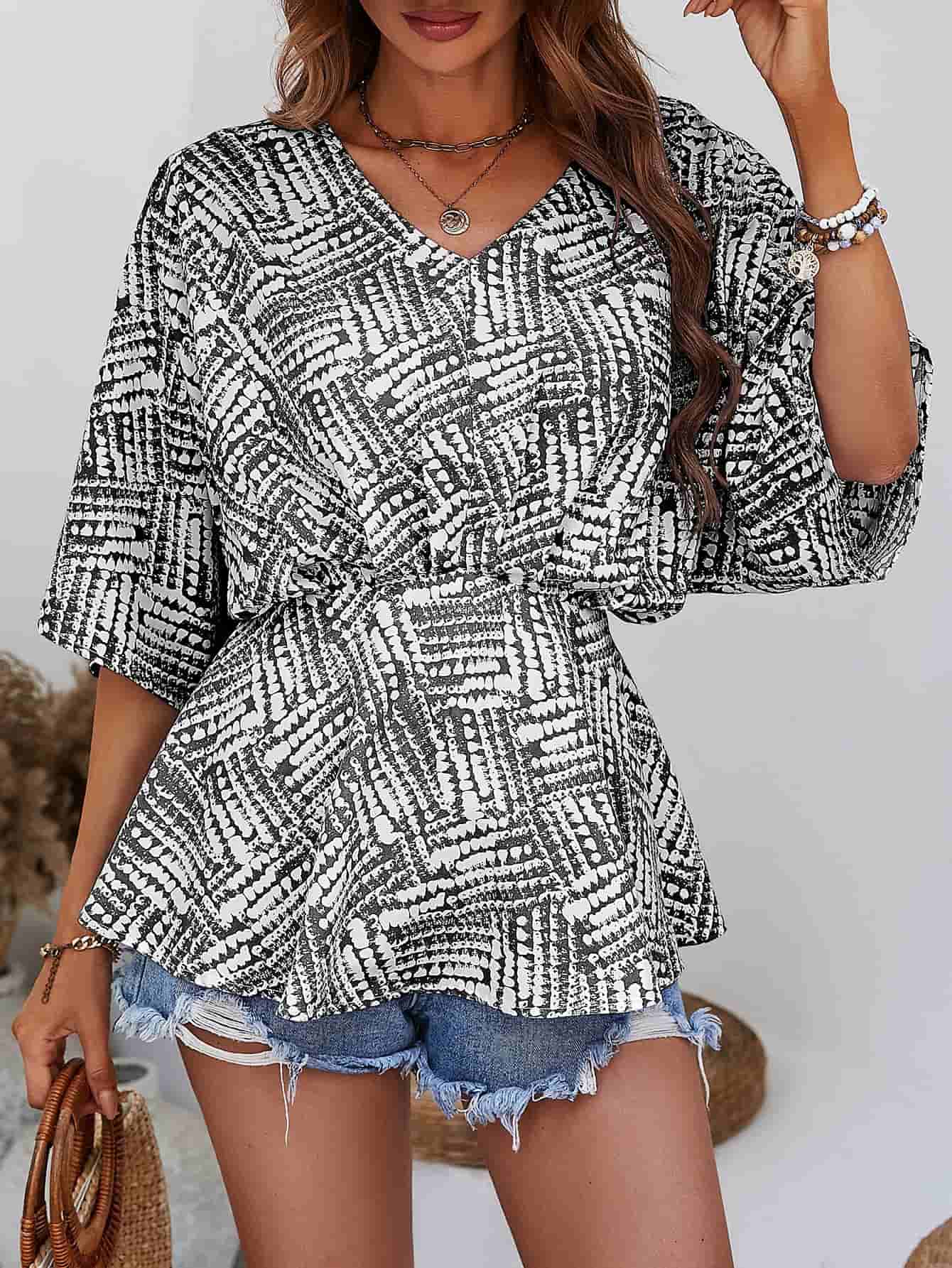 Abstract print cinched waist blouse with V-neck and short sleeves in black and white.