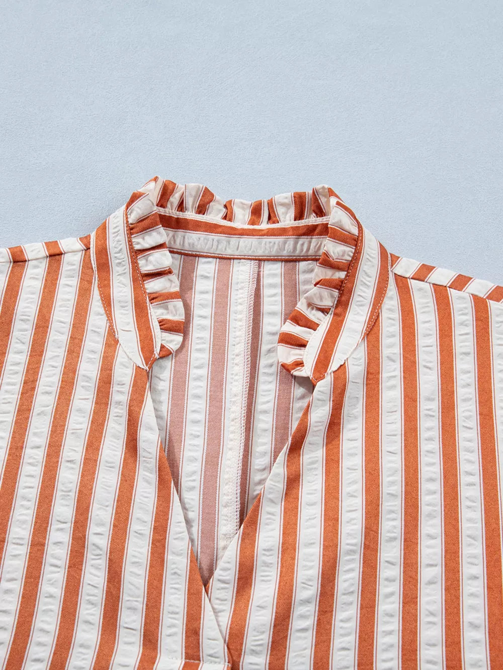 Striped V-neck mini dress with ruffled collar and textured fabric.