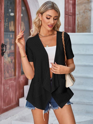 Black perforated shawl collar jacket with short sleeves and open front, styled with a white crop top and denim shorts.