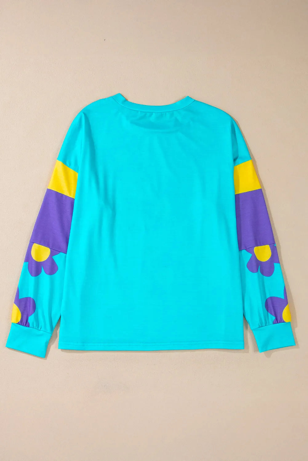 Crewneck long sleeve top in pastel blue with colorblock sleeves featuring purple and yellow daisy print.