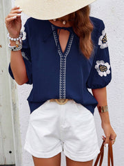 Dark blue blouse with embroidered yoke, tie neck, and puff sleeves.