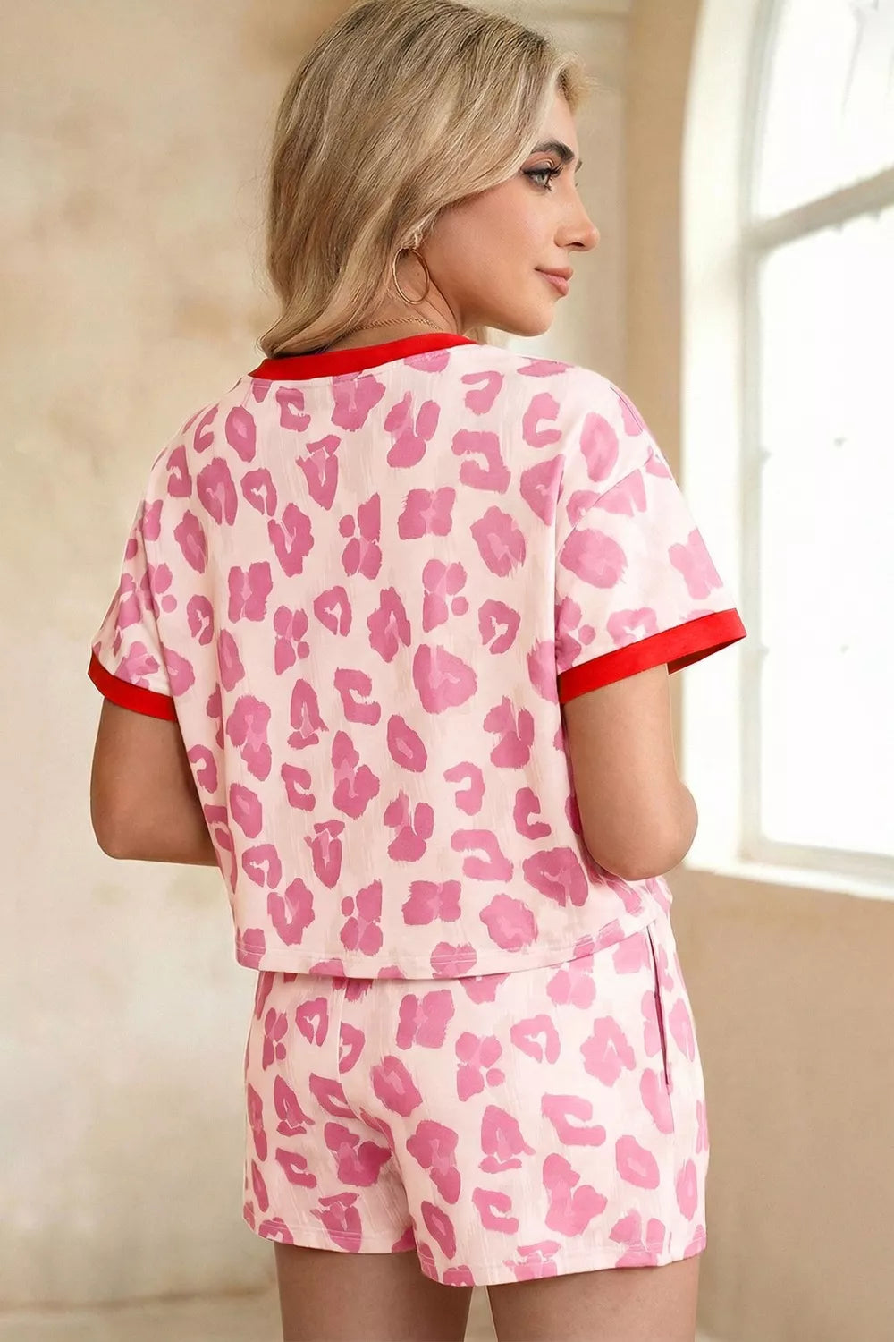 Pink leopard print pajama set with red trim, polyester shorts and short sleeve top.