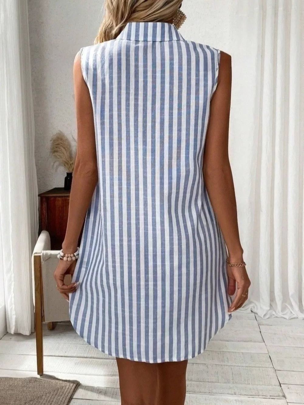 Sleeveless collared shirt dress in light blue and white vertical stripes, above the knee length.