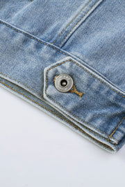 Medium wash denim trucker jacket detail with metal snap button closure and contrast stitching.