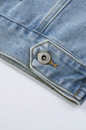Medium wash denim trucker jacket detail with metal snap button closure and contrast stitching.
