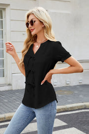 Black textured blouse with tie-front detail and short sleeves.