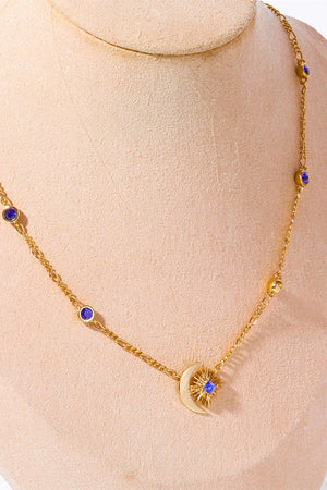 Gold celestial necklace with sunburst, crescent moon, and blue gem accents