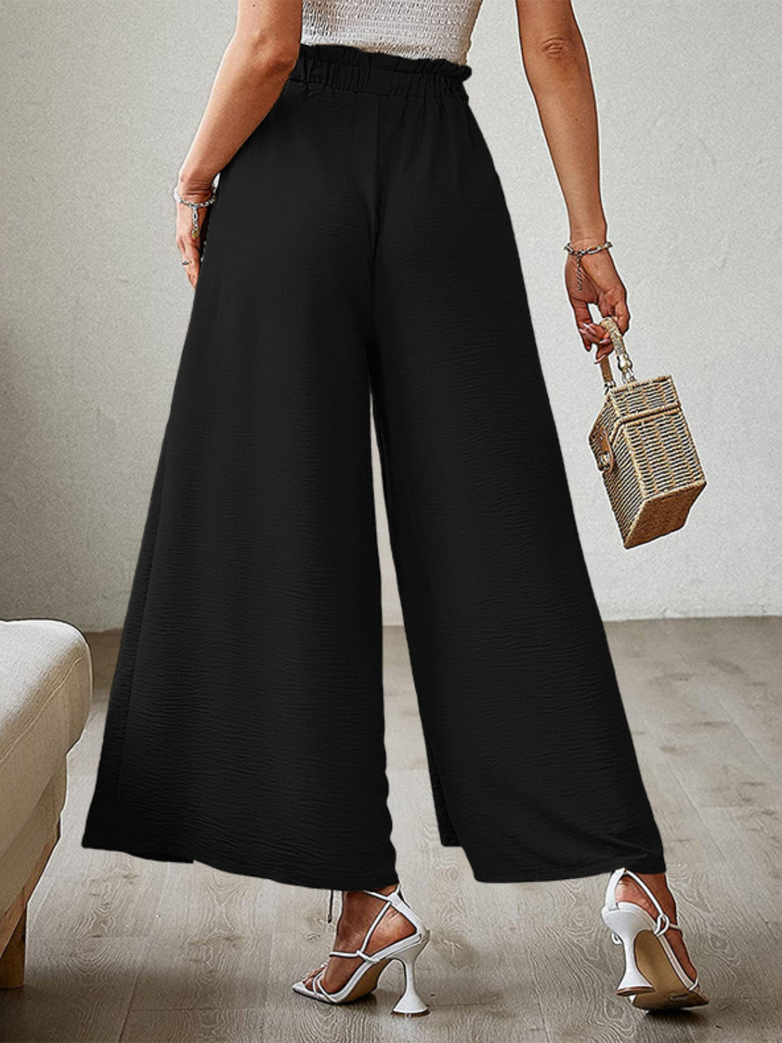 Black paperbag waist palazzo pants with side slits and textured fabric.