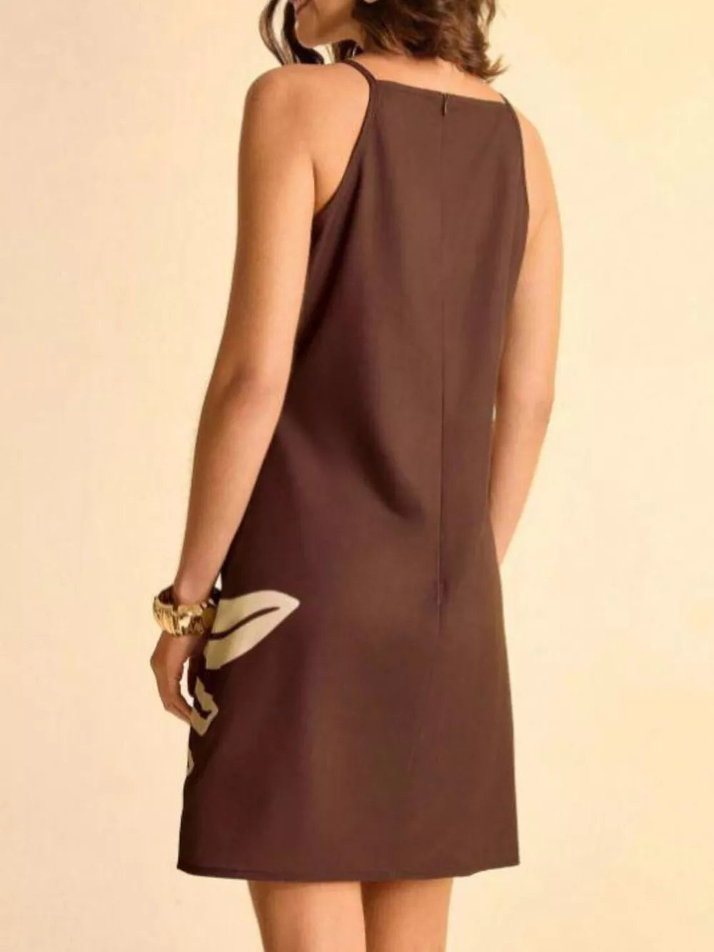 Brown mini dress with cream tropical leaf print, a-line cut, and spaghetti straps.