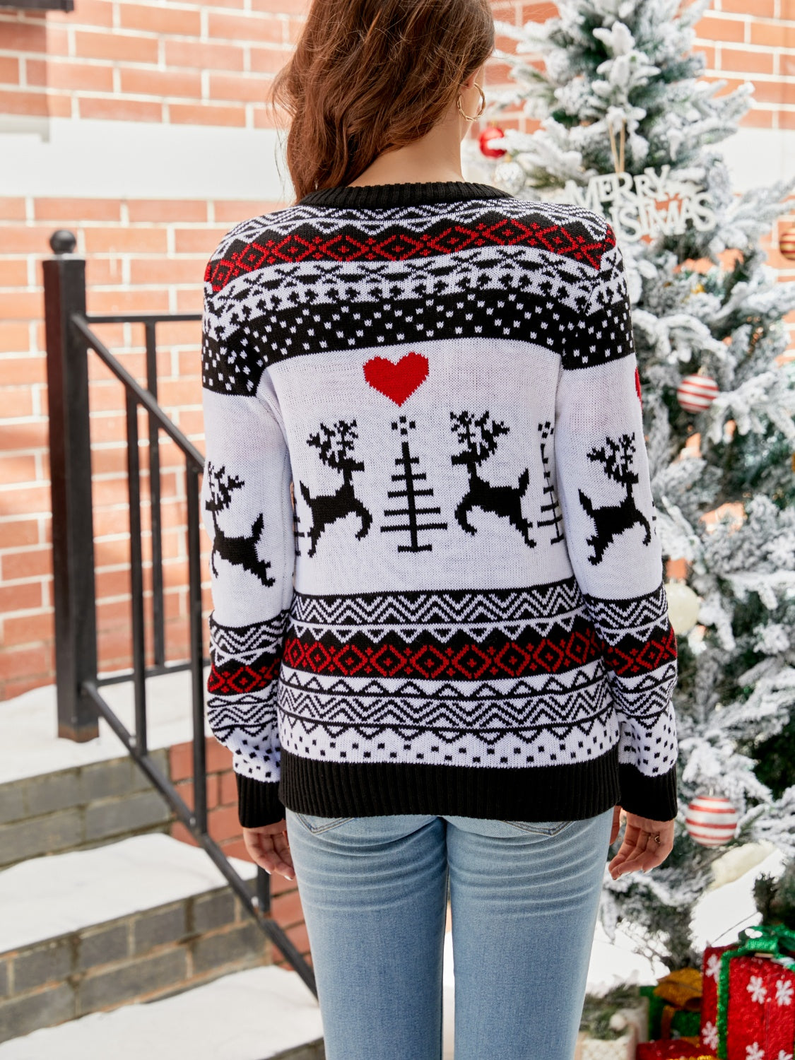 White acrylic crewneck sweater with black and red Fair Isle reindeer and heart pattern.