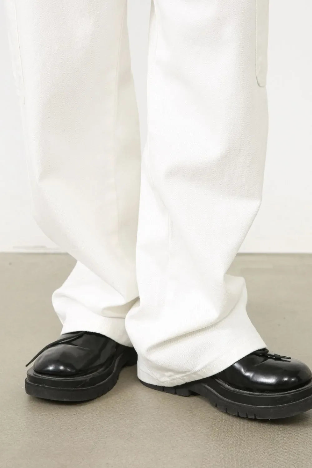 White 100% cotton pleated cargo pants with a wide leg cut.