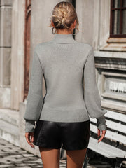 Gray turtleneck knit sweater with pearl button cuffs and ribbed details.