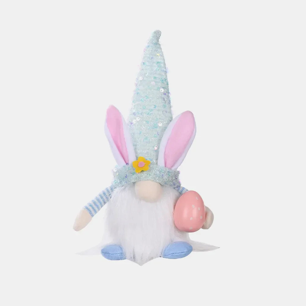 Easter bunny gnome in light blue with sequin cone hat, holding pink egg.
