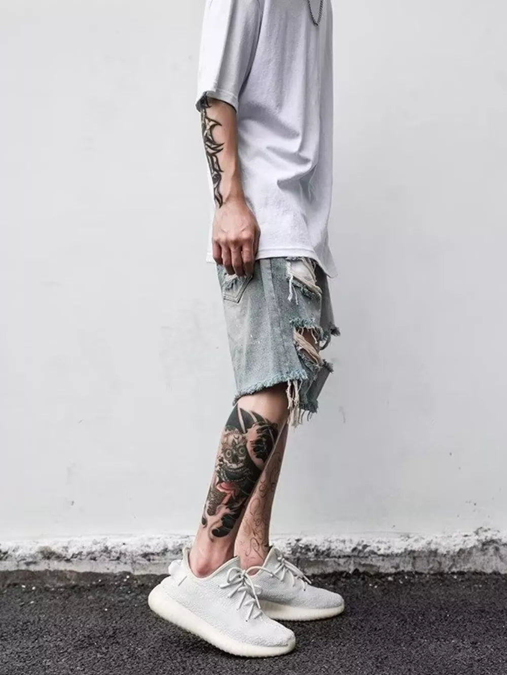 Men's light blue distressed denim shorts with heavy rips and frayed hems.