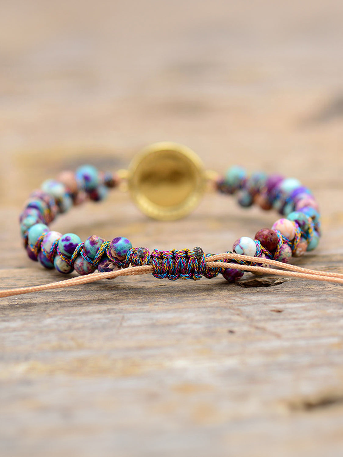 Multicolor beaded bracelet with iridescent orb and jasperite beads, adjustable cord closure.