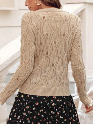 Beige V-neck knit sweater with openwork pattern and pearl details.
