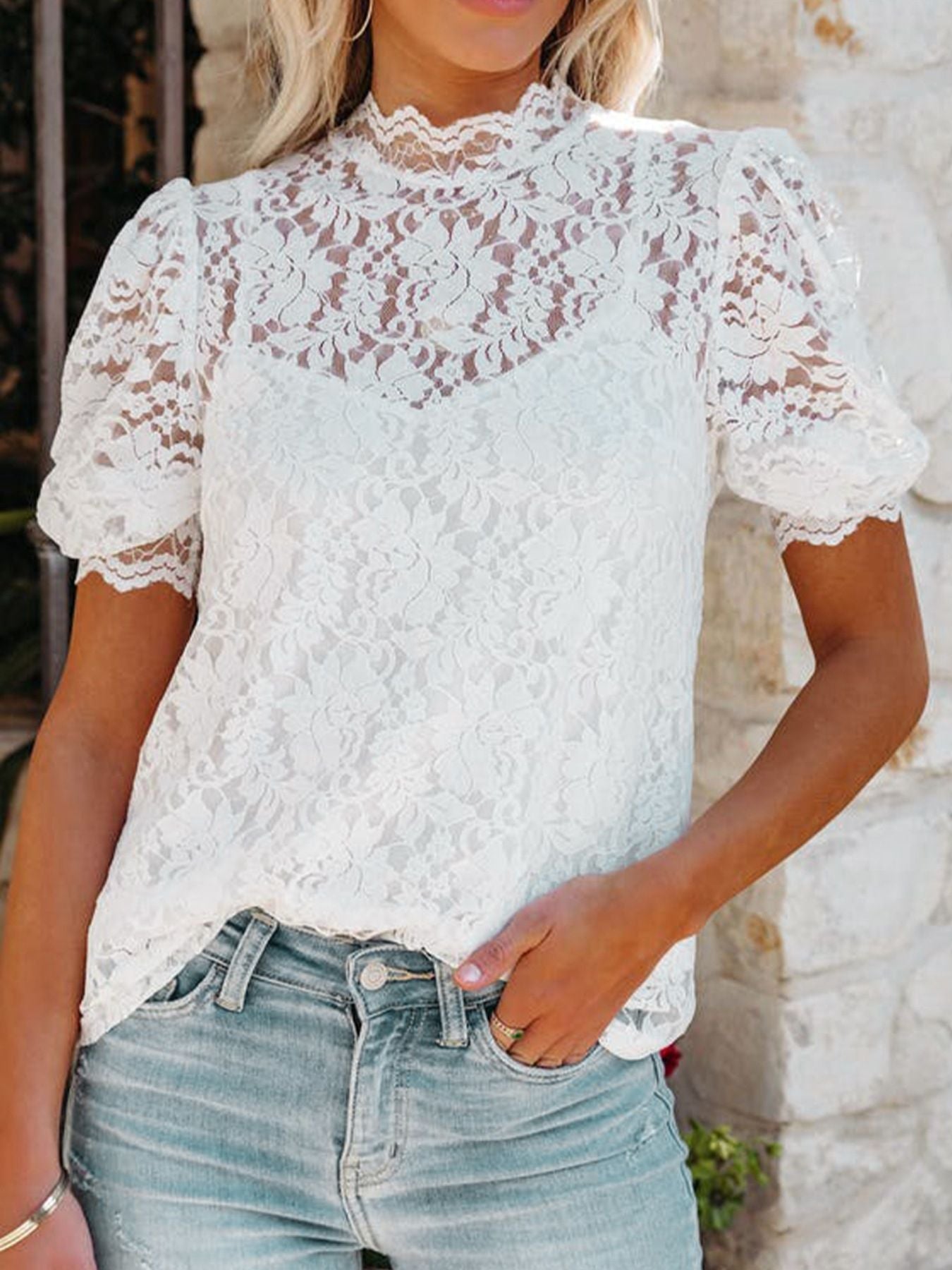 White lace short sleeve blouse with mock neck and puff sleeves, worn with jeans.