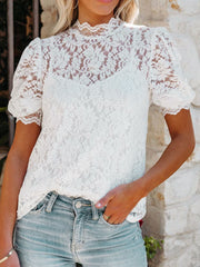 White lace short sleeve blouse with mock neck and puff sleeves, worn with jeans.