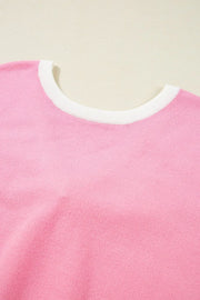 Pink knit blouse with white contrast trim neckline and back bow detail.