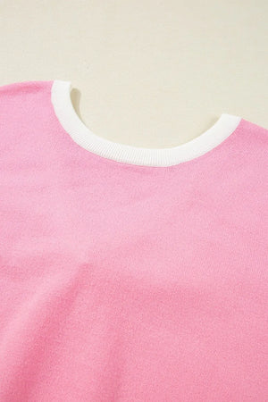 Pink knit blouse with white contrast trim neckline and back bow detail.