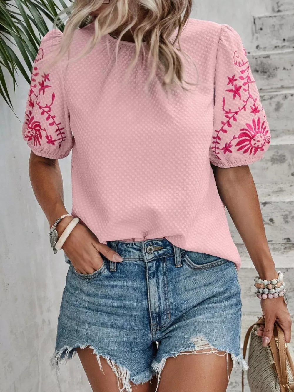 Pink embroidered puff sleeve blouse with textured fabric and floral sleeve detail.