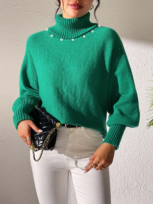 Green turtleneck sweater with dolman sleeves and pearl embellishments at the neckline.