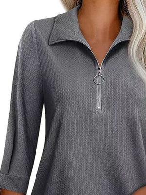 Textured dark gray zip-front polo top with a ring zipper pull.